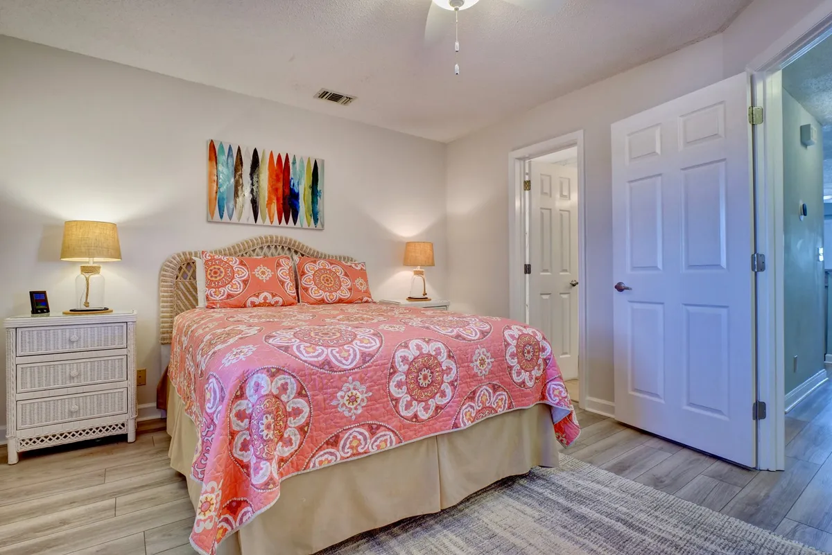 A second inviting bedroom featuring a bed with richly patterned bedding, colorful wall art, and nightstands topped with lamps. The space feels welcoming, ideal for unwinding, and offers ample storage for personal belongings.